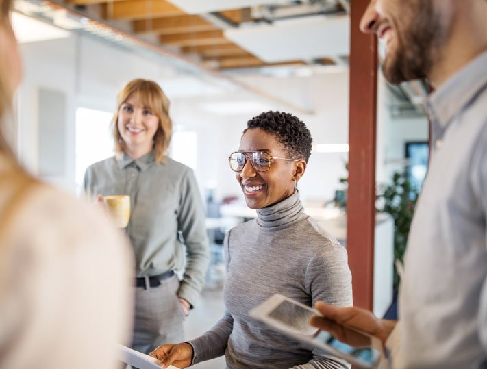 Group of colleagues in conversation in open plan office